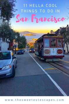 a cable car traveling down a street next to a blue car and some cars parked on the side of the road