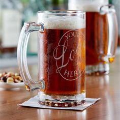 two mugs of beer sitting on top of a wooden table