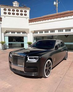 a black rolls royce parked in front of a building