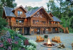 a large log home with two fire pits in the front yard