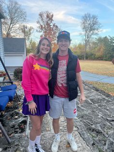 a young man and woman standing next to each other in front of a house on a sunny day