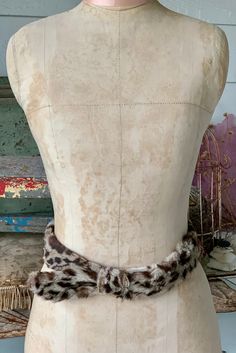 a mannequin with a fur collar on it's neck and an animal print belt around the waist