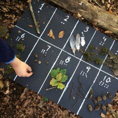 a person standing next to a game board with numbers and leaves on it