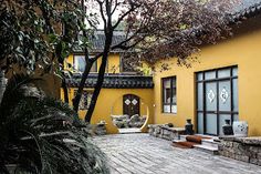 a yellow house with a tree in the front yard and stone steps leading up to it