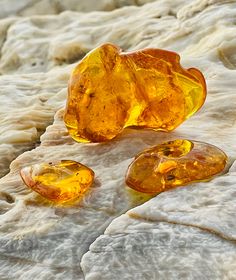 three pieces of yellow glass sitting on top of a white tablecloth covered in ice