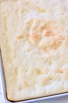 a square pan filled with batter on top of a white countertop next to a wooden table