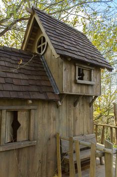 a small wooden house with a bench in front of it and a tree behind it