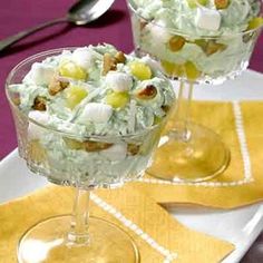 two glasses filled with dessert sitting on top of a table