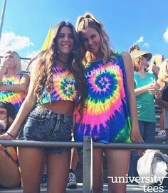 two young women standing next to each other in front of a crowd at a sporting event