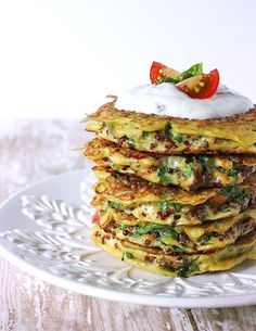 there is a stack of pancakes on the plate with whipped cream and tomatoes in the middle