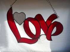 a red love sign hanging from a chain with a heart shaped cutout on it