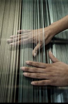 two hands are weaving fabric on a loom with the help of an adult's hand