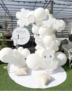 a bunch of balloons sitting on top of a white table cloth covered field with bunnies