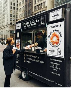 a woman standing in front of a food truck selling hot dogs and other foods on the street