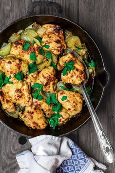 chicken and artichokes in a skillet with a spoon on the side