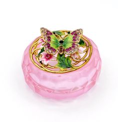 a pink glass box with a butterfly on it's lid and flowers in the center