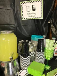 the table is set up with green and black cups, bottles, and straws