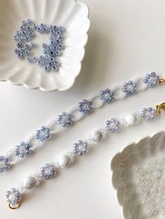 a white and blue beaded necklace next to a plate with a flower on it