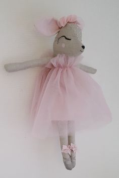 a stuffed mouse in a pink dress hanging on the wall