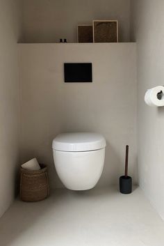 a white toilet sitting in a bathroom next to a roll of toilet paper on the wall