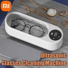 an ultrasonic glass cleaning machine on a table with gold chains and watches around it