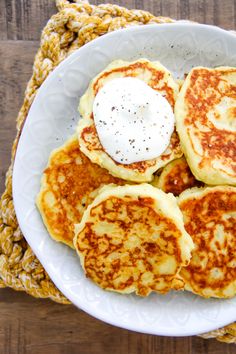 four pancakes on a white plate topped with whipped cream