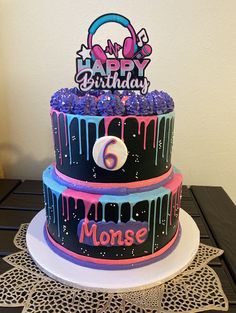 a three tiered birthday cake with purple and blue icing on the bottom layer