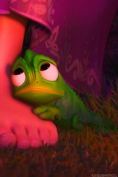 a green frog sitting next to a person's legs