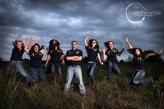 a group of young women standing on top of a lush green field under a cloudy sky