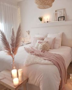 a white bedroom with candles and blankets on the bed