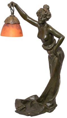 a bronze statue with a lamp on it's arm