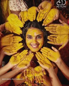 a group of people covered in yellow powder holding hands up to the camera with their faces painted