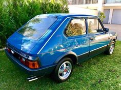 a blue car parked on top of a lush green field