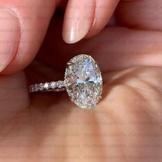 a close up of a person holding a ring with a large diamond in the middle