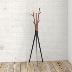 a wooden floor standing next to a white brick wall with three black metal branches on it