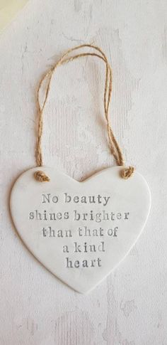 a ceramic heart hanging on a wall with the words no beauty shines brighter than that of a kind of heart