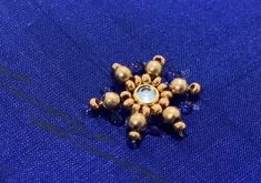 a gold and blue brooch sitting on top of a blue cloth