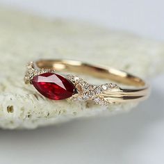 a close up of a ring with a red stone in it on top of a rock