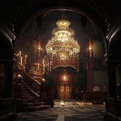 a large chandelier hanging from the ceiling in a dark room with stairs leading up to it