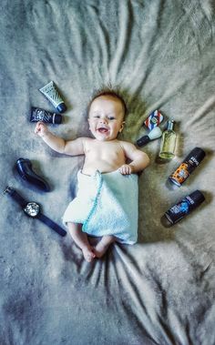 a baby laying on top of a bed next to shoes and hairbrushes,