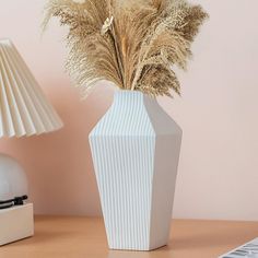 a white vase sitting on top of a table next to a lamp and a keyboard