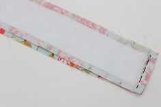 an empty piece of fabric sitting on top of a white tablecloth covered with pink and yellow flowers