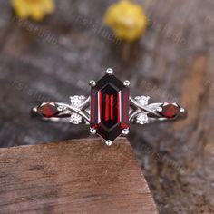 a ring with an oval cut garnetia stone surrounded by small white diamonds on a wooden surface