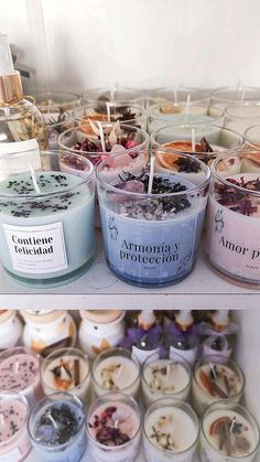 several jars filled with different types of candles on top of a shelf next to each other