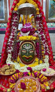 there is a statue that has been decorated with flowers and garlands on it's head