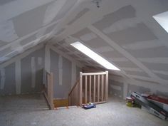 an unfinished attic with white walls and stairs