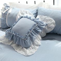 two blue pillows with ruffled edges and white lace trim on the pillowcases