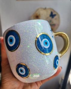 a hand holding a coffee cup with blue and white eyes painted on the inside of it