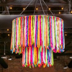 a multicolored chandelier hanging from the ceiling in a room with exposed lighting