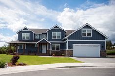 a large blue house with two garages in the front yard